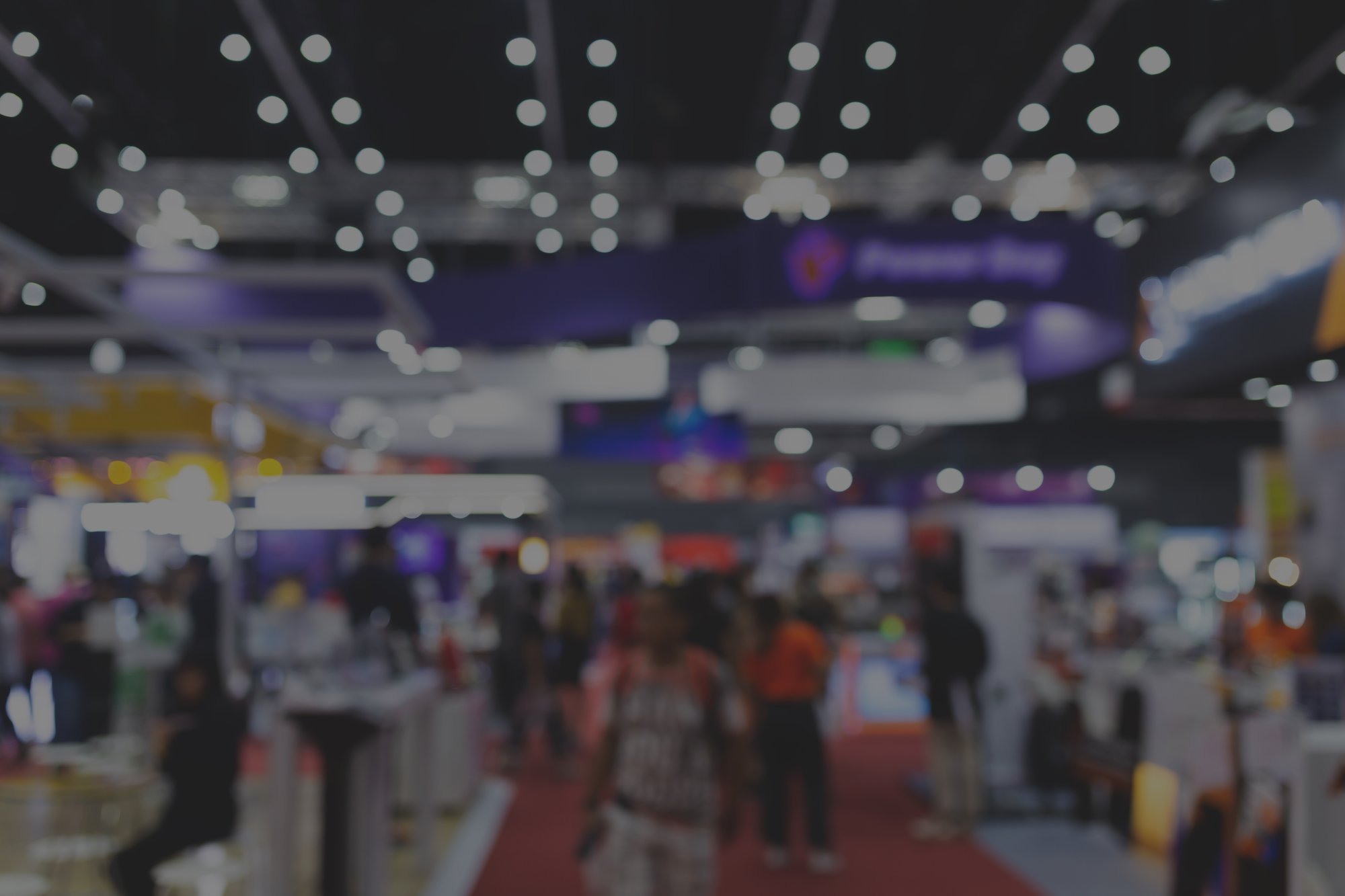 an out of focus image of a convention floor with people and booths