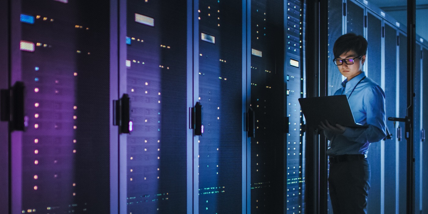 A male employee looking at server racks in a futuristic data center.